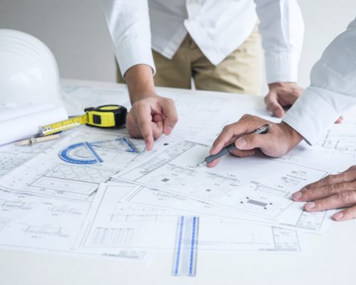 construction-engineering-or-architect-discussing-a-blueprint-and-building-model-while-checking_t20_A97doP